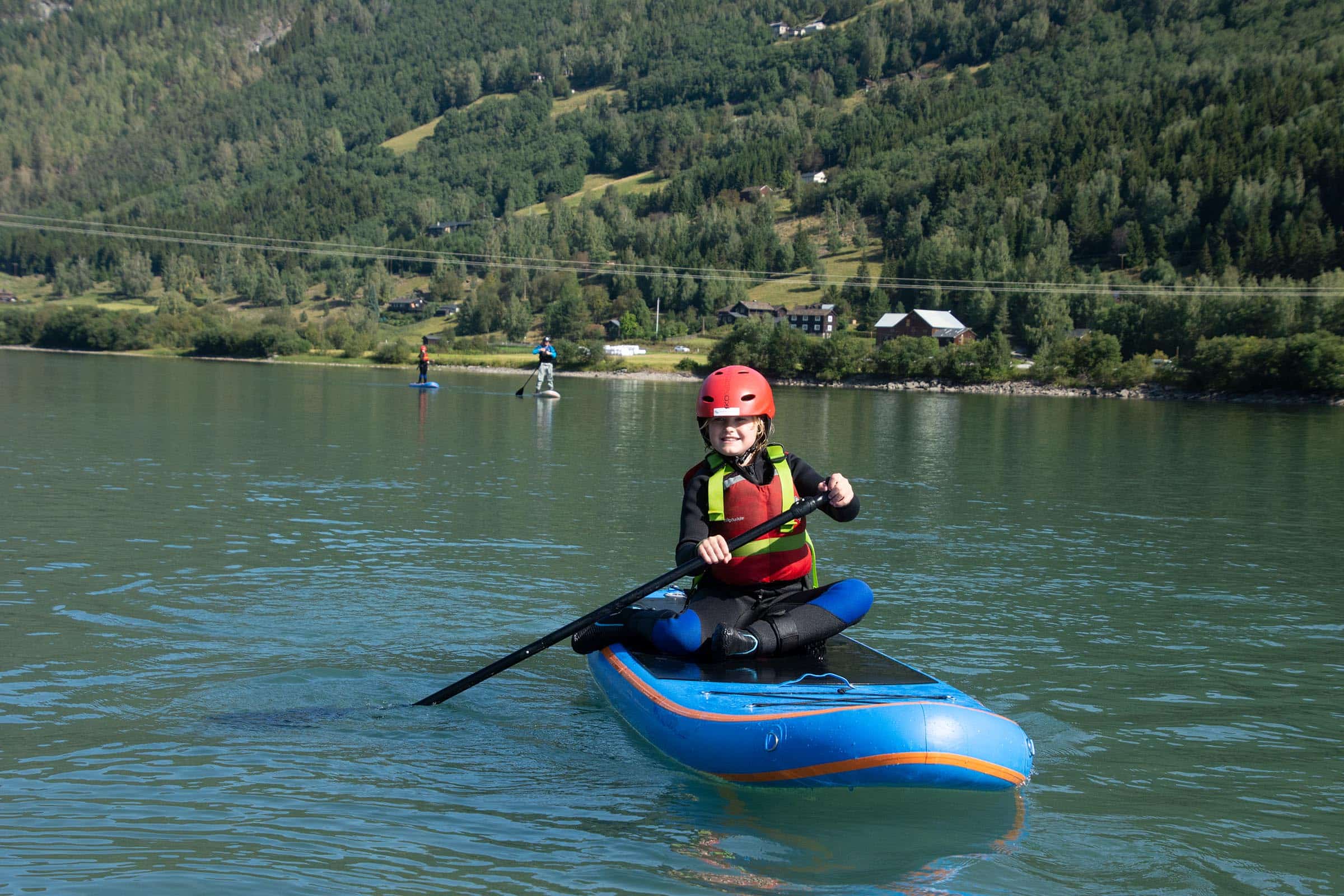 Jente som sitter å padler på SUP brettet