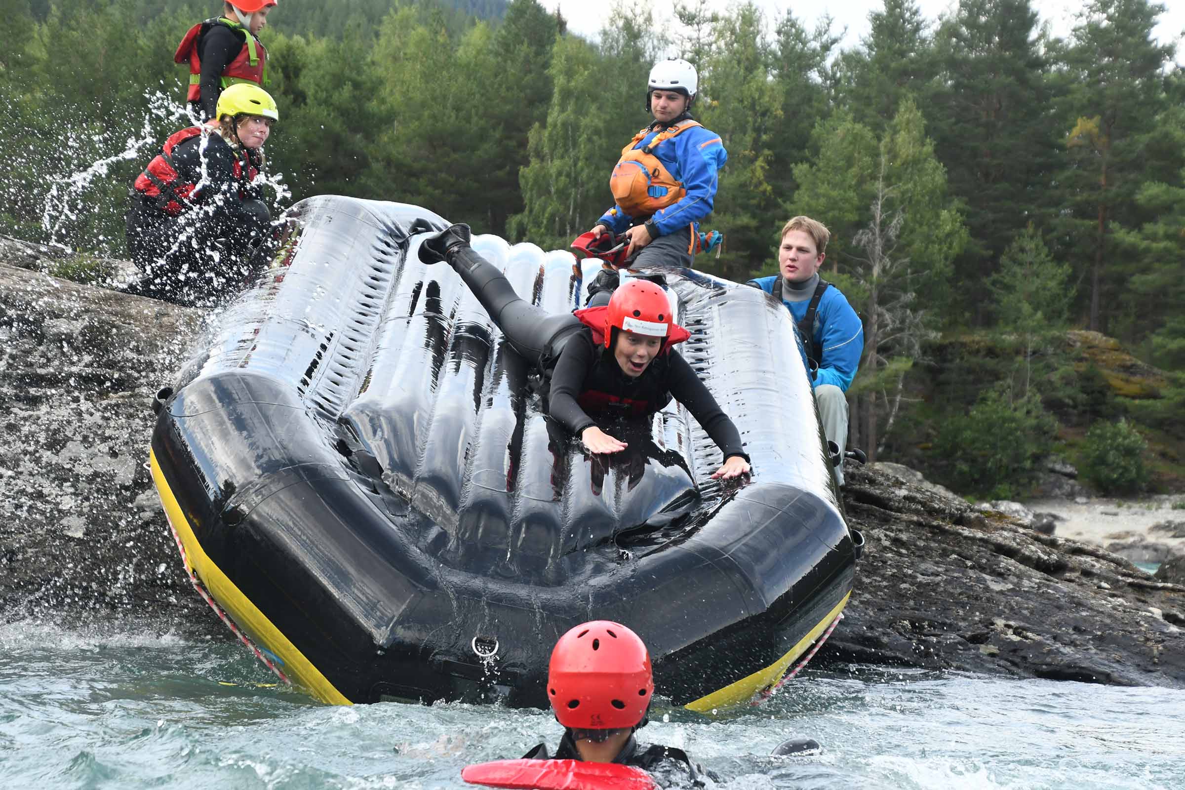 Raftingbåt som ligger opp ned blir brukt som en vannsklie fra land og ut i vannet